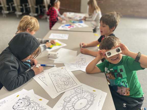 Four kids sitting at a table coloring art projects